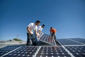 Engineers Positioning Solar Panel Against Sky