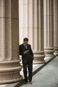 Indian businessman or Lawyer using a Smart Phone outside a colonial courthouse building.